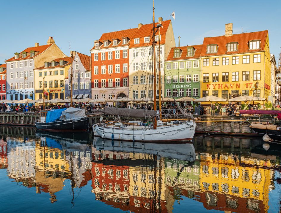Maritime Infrastruktur und traditionelle Handelsschiffe vor den bunten Giebelhäusern der Logistikmetropole Kopenhagen.