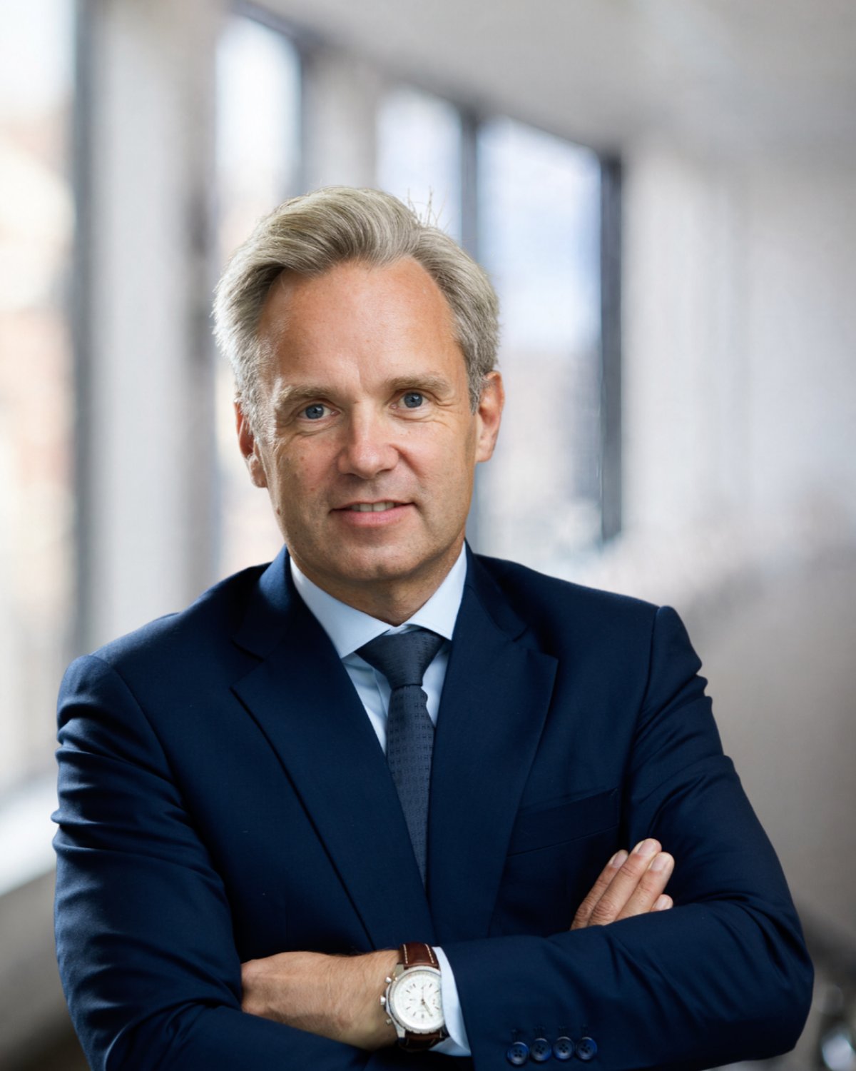 Porträt von Jo De Wolf, CEO von Montea, im dunkelblauen Anzug mit verschränkten Armen
