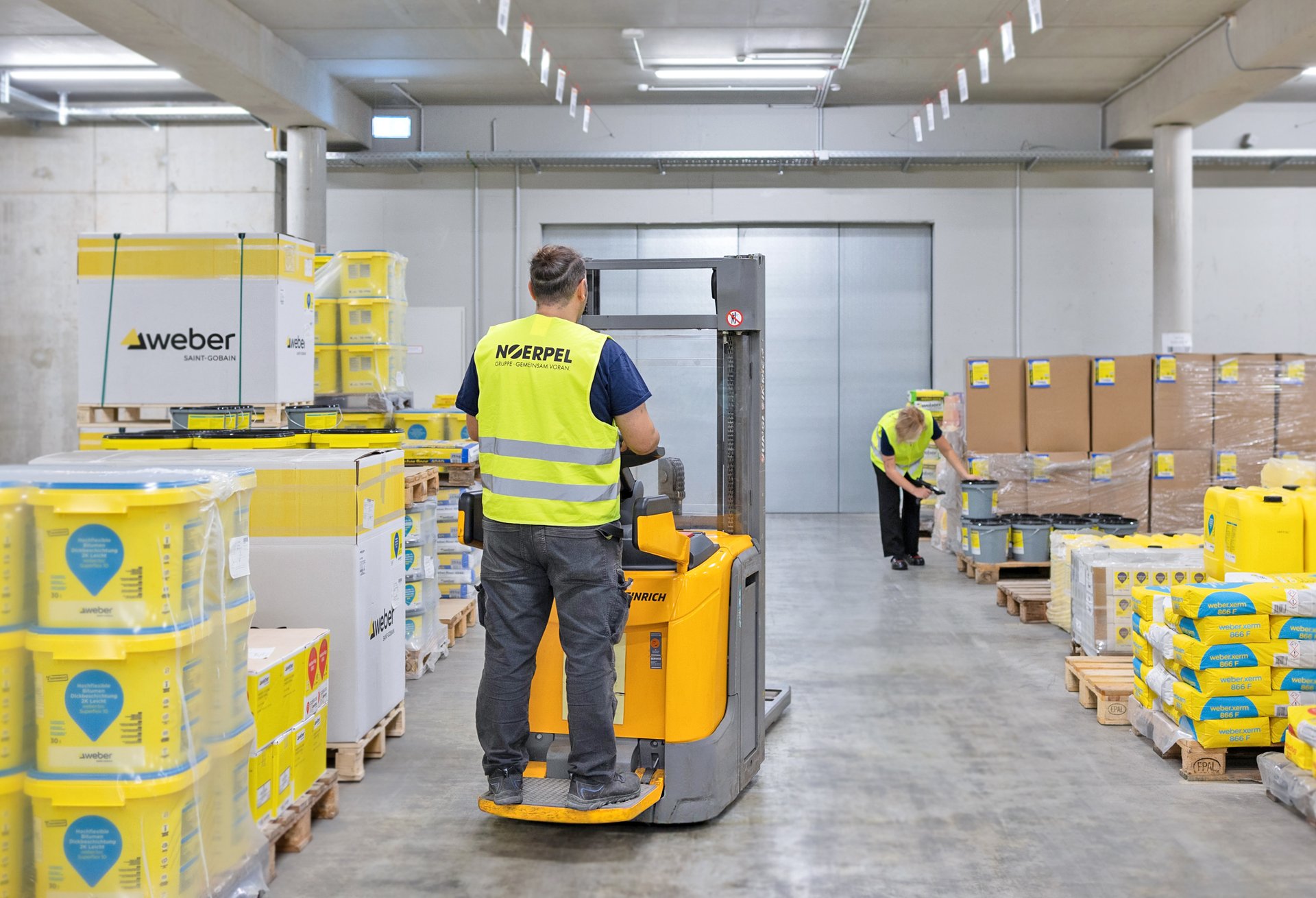 Noerpel employee with an industrial truck between pallets of Weber construction chemicals products in the warehouse at Noerpel's headquarters in Ulm
