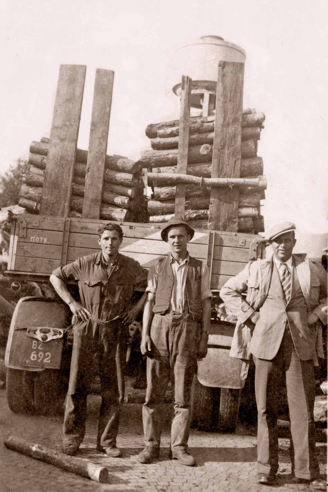 Historisches Foto aus den 1950er-Jahren: Firmengründer Josef Gruber (rechts) mit zwei Männern vor einem mit Holzstämmen beladenen Lkw mit Bozner Kennzeichen